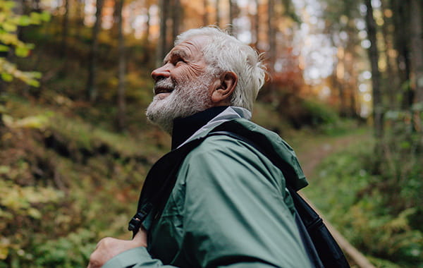 Gentleman hiker wearing a waterproof coat while walking through an autumnal forest.