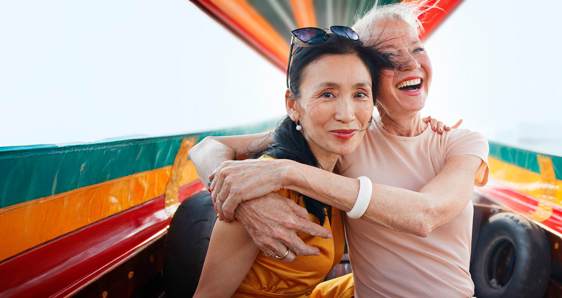 Two female friends embracing in happiness while enjoying a boat ride on holiday.