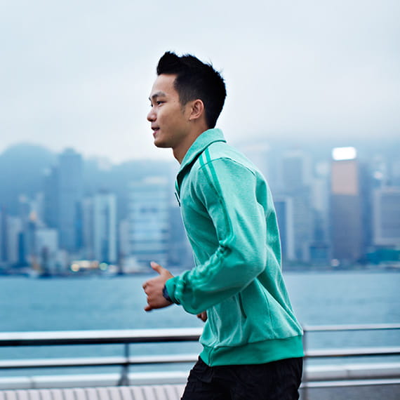 Man jogging on a bridge overlooking a city on the other side of the water