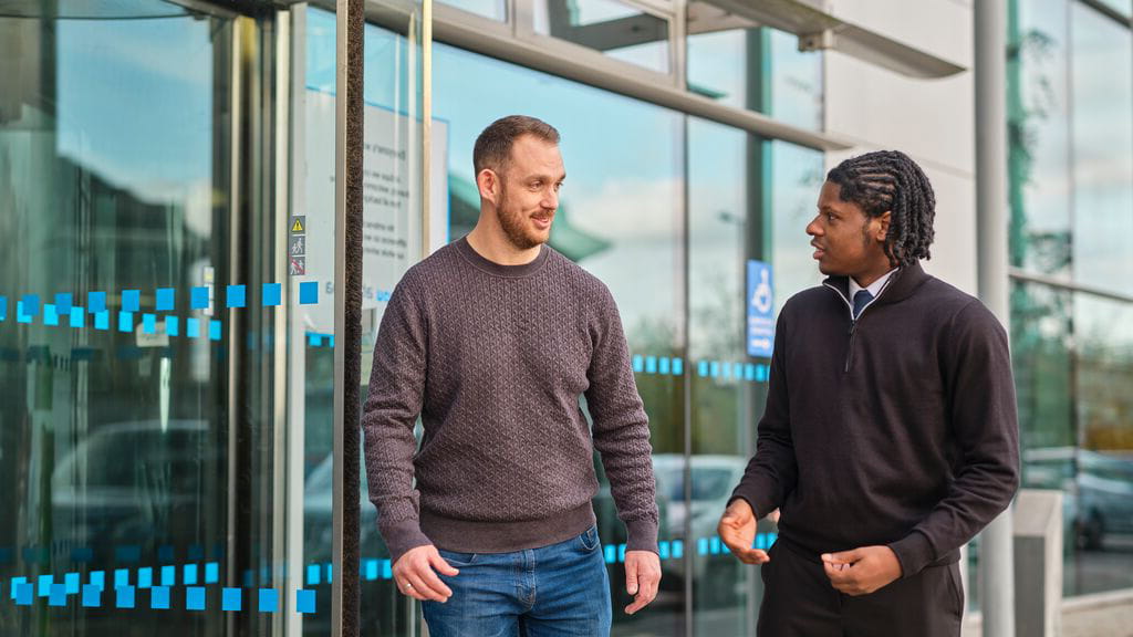 Image of two men walking and talking together