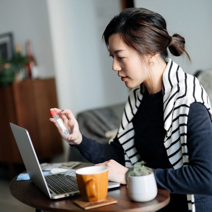 Woman holding a medical vial while speaking on a video call