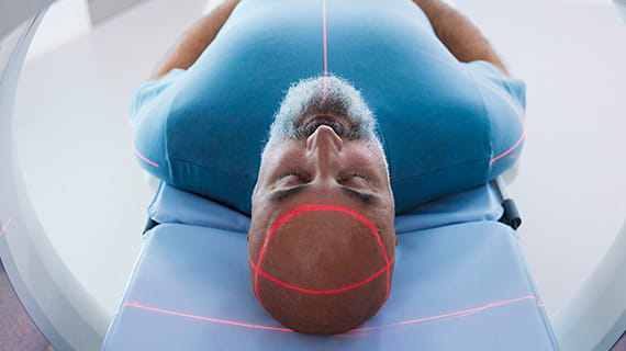 Man in a blue t-shirt undergoing a brain scan