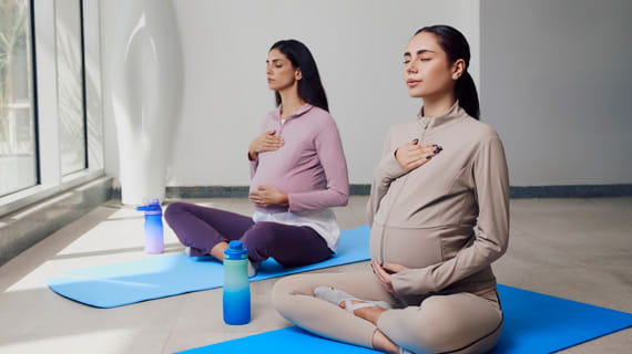 Two pregnant women peacefully doing yoga