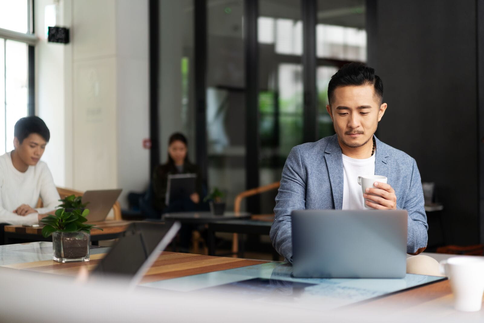 Person hotdesking in an office with coffee in hand