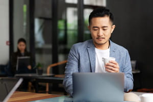 Person hotdesking in an office with coffee in hand