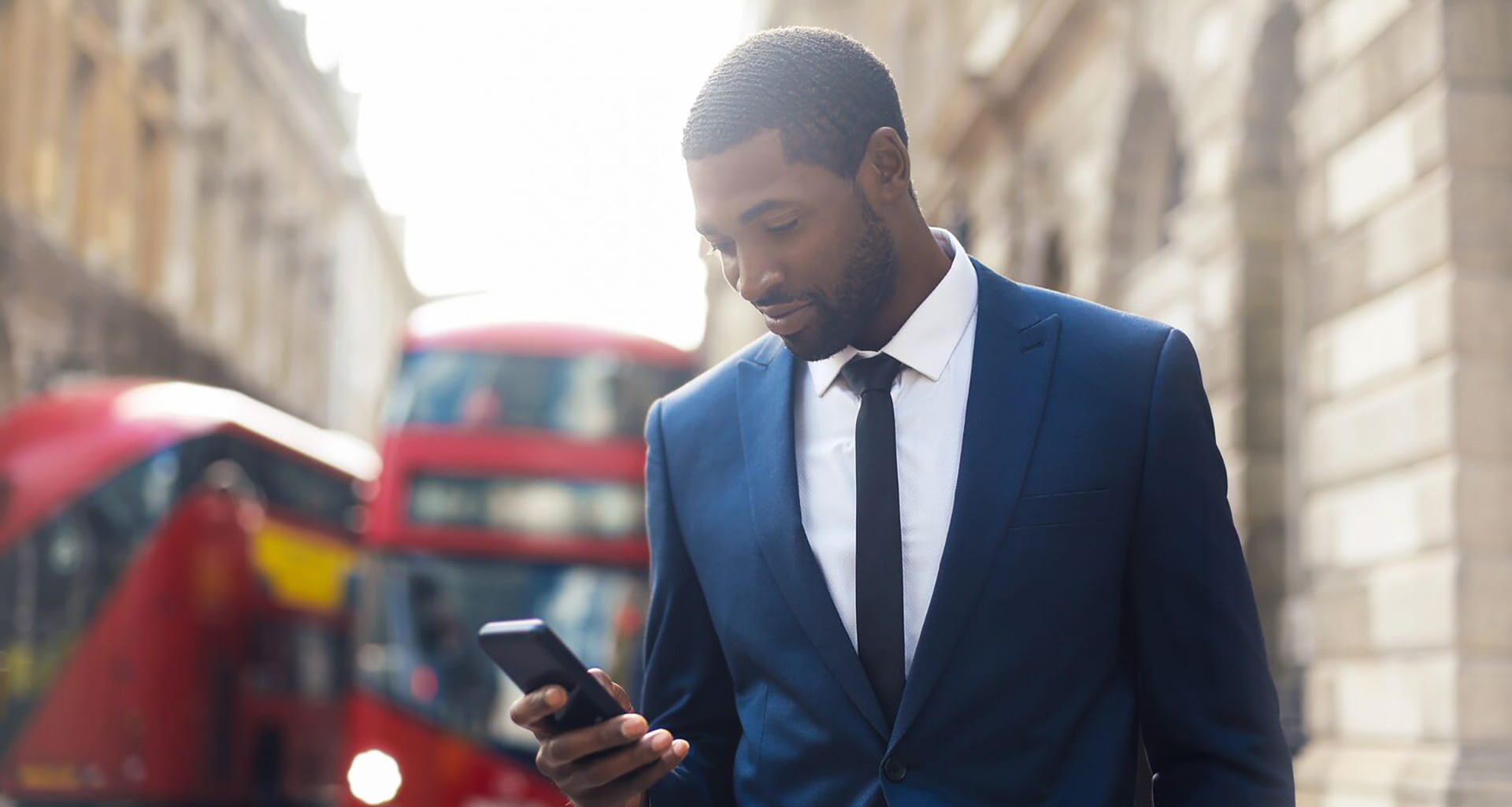 Man in a suit in London looking at his mobile phone