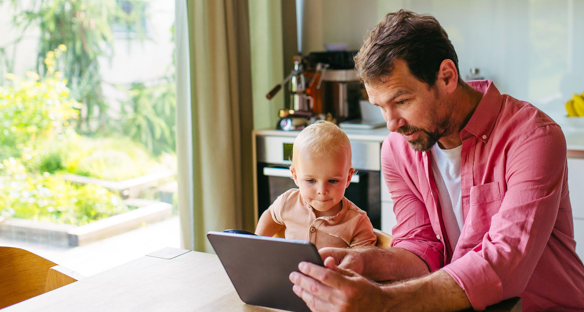 Father and young child looking at a tablet in a kitchen