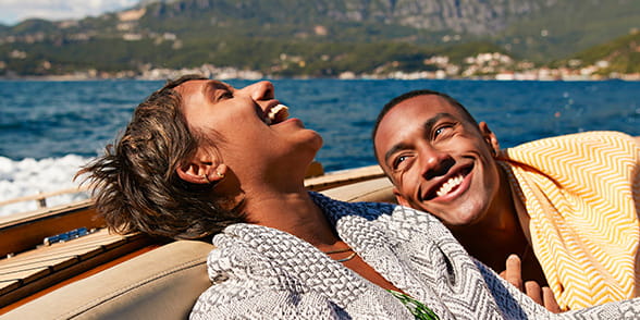 Man and woman relaxed and laughing while enjoying a boat ride in a sunny climate.