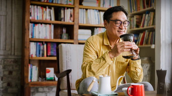 person appreciating the smell of coffee in home library