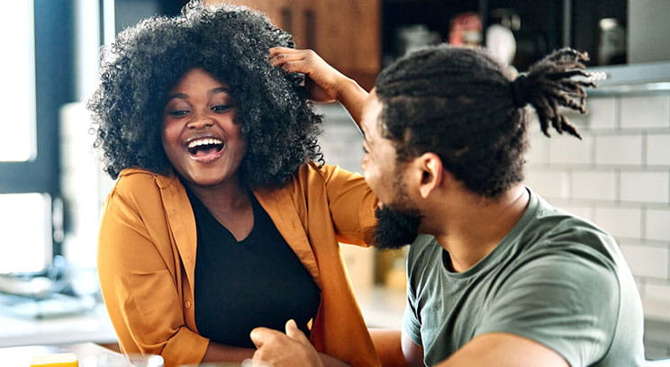 Two smiling people talk at kitchen table over breakfast