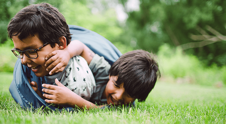 Two children playing together in the grass