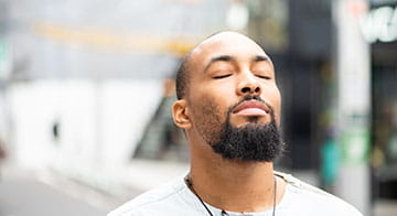 Man standing with eyes closed having a calm, mindful moment 