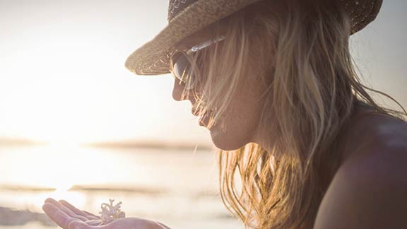 Woman holding a coral against sunset