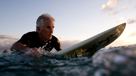 grey haired man surfing
