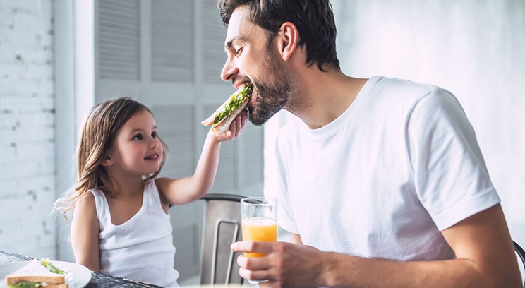 Daughter feeds dad a sandwich 