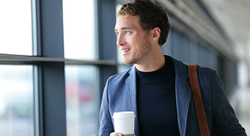 Man drinks coffee at airport terminal