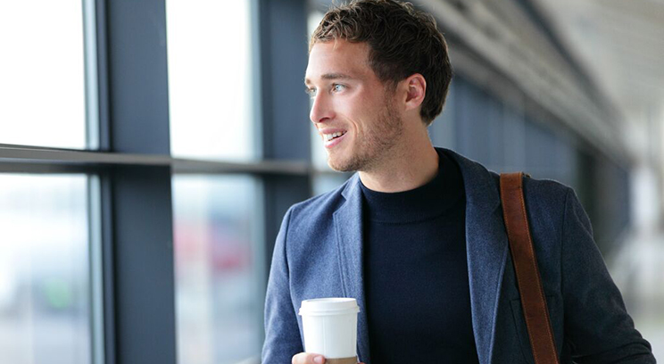 Man drinks coffee at airport terminal