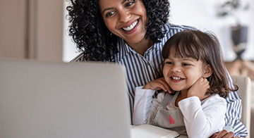 Woman of colour and child smiling using laptop