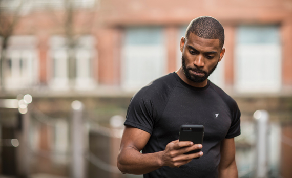 Man looking down at smartphone while wearing gym clothes
