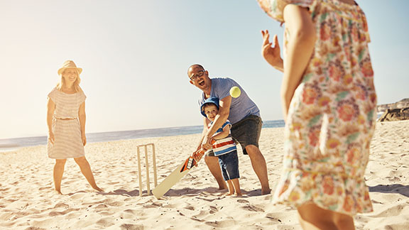 Family playing cricket on the beach 