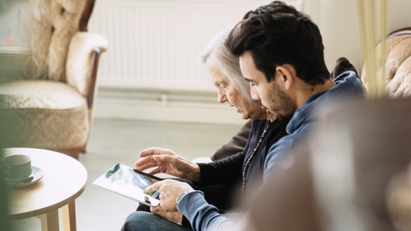 younger man showing older woman how to use a tablet