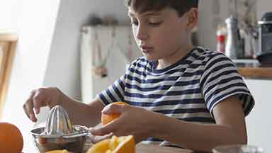 Boy squeezing orange juice in the kitchen 