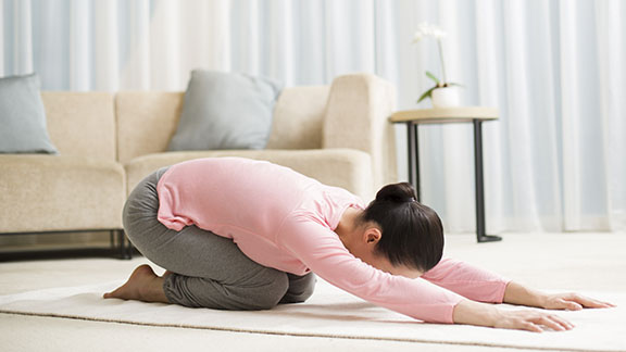 Woman practising yoga in hotel room. Juggling exercise and travel can be tricky.