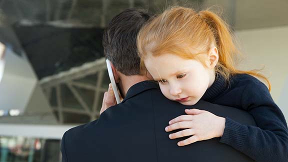 Man on the phone holding a little girl